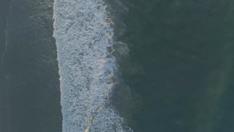 Aerial-shots-of-breaking-waves-on-a-hazy-summer-morning-in-Malibu,-California