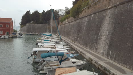 Langsame-Neigung-Enthüllt-Kleine-Boote-In-Einem-Hafen-Und-Die-Alten-Alten-Stadtmauern-Von-Zadar,-Kroatien