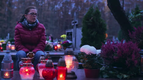 Woman-in-grief-at-a-grave-lit-by-burning-grave-candles