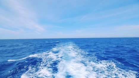 Upper-level-view-of-wake-behind-yacht,-tilt-up-revealing-Caribbean-Sea-horizon