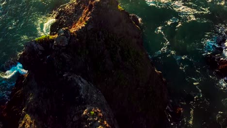 Overhead-sunset-view-of-rocky-cliffs-and-green-ocean-waves-in-Big-Sur-California