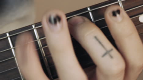Hands-with-a-shabby-black-nail-polish-playing-the-guitar