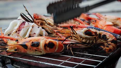 a-side-view-of-grilled-shrimps-that-are-being-turned-by-a-thai-girl,-Thailand