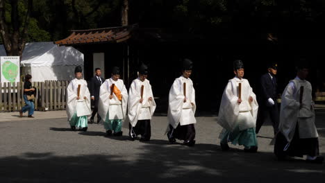Sacerdotes-Sintoístas-Vestidos-Con-Túnicas-Heian-Caminando-En-Fila-En-El-Santuario-Meiji-Jingu,-Parque-Yoyogi