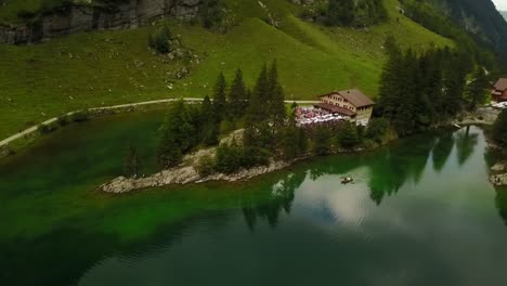 look-from-above-on-a-calm-green-lake-with-boat-and-a-hotel-in-between-the-trees