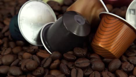 turning-view-of-Nespresso-coffee-capsules-on-roasted-coffee-beans,-rotating-spinning-4k-footage-of-coffee-pods