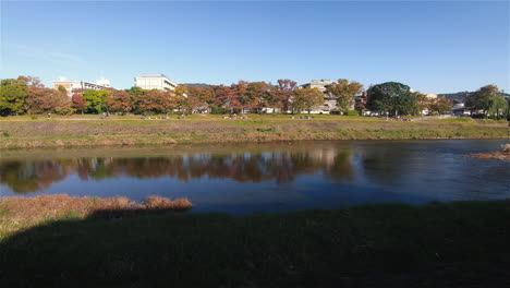 Una-Hermosa-Toma-Panorámica-Del-Río-Kamogawa-Que-Fluye-Río-Abajo-En-Kyoto,-Japón,-Durante-La-Tarde-De-Otoño