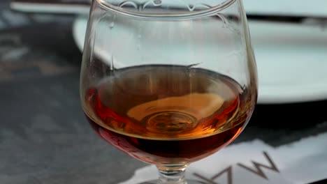 Glass-of-Greek-Metaxa-Spirit-drink-close-up-while-people-are-dinning