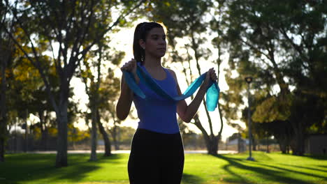 A-beautiful-young-woman-using-resistance-bands-in-her-outdoor-workout-and-exercise-training-at-sunset-SLOW-MOTION
