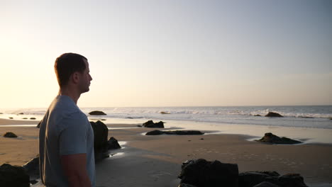 Ein-Starker,-Gut-Aussehender-Mann,-Der-Die-Meereswellen-Beobachtet-Und-Sich-Auf-Ein-Morgendliches-Training-Am-Strand-Bei-Sonnenaufgang-In-Santa-Barbara,-Kalifornien,-Zeitlupe-Vorbereitet