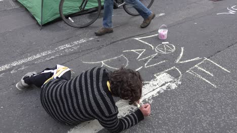 Un-Manifestante-Dibuja-En-El-Suelo-Con-Tiza-En-Las-Protestas-De-Rebelión-De-Extinción-En-Londres,-Reino-Unido