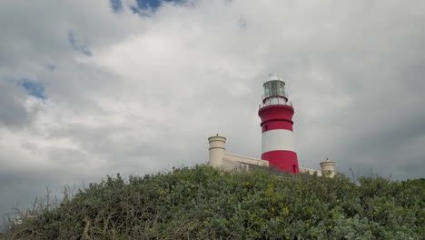 Zeitraffer-–-Der-Zweitälteste-Leuchtturm-Südafrikas,-Der-Noch-In-Betrieb-Ist,-Leuchtturm-Von-Cape-Agulhas-Mit-Ziehenden-Wolken-Im-Hintergrund