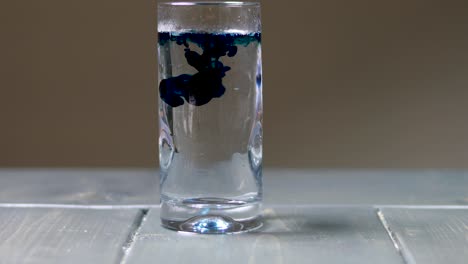 Tropfen-Blauer-Lebensmittelfarbe-In-Ein-Glas-Wasser-Tropfen