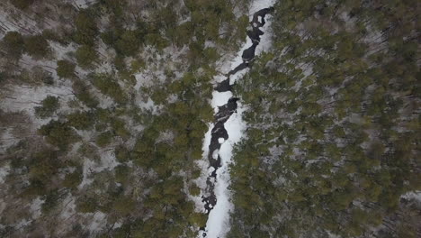 Drone-flying-high-above-snowy-mountain-river-in-winter