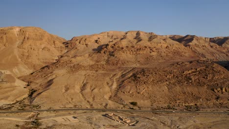 Aerial-pan-shot-of-red-mountain-ridge-of-Judea-desert-Israel,-clear-sky-day