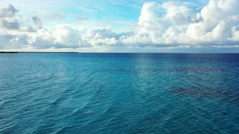 Aquamarinblaue,-Lebendige-Meeresoberfläche,-Die-Einen-Wunderschönen-Himmel-Mit-Weißen-Wolken-Widerspiegelt,-Die-Vom-Meereshorizont-Zum-Hellblauen-Himmel-In-Der-Dominikanischen-Republik-Aufsteigen