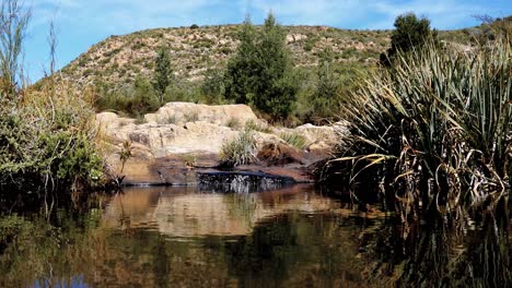 Tranquil-scene-of-water-falling-into-fresh-water-pool-in-mountains-of-remote-area-outside-Oudtshoorn,-South-Africa