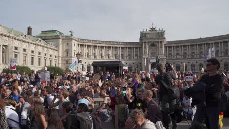 Crowd-of-people-gathered-during-protests-in-Vienna,-with-backdrop-of-national-library