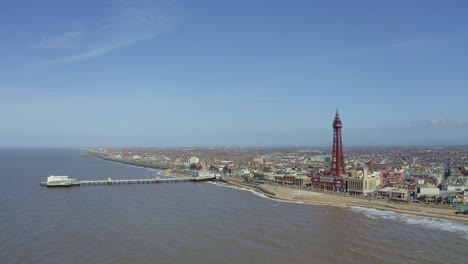Stunning-aerial-view,-footage-of-Blackpool-Tower-from-the-sea-of-the-award-winning-Blackpool-beach,-A-very-popular-seaside-tourist-location-in-England-,-United-Kingdom,-UK