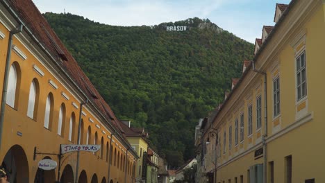 Downward-tilt-From-the-mountains-to-the-market-road-Hiding-the-Brasov-Sign-in-Brasov,-Romania