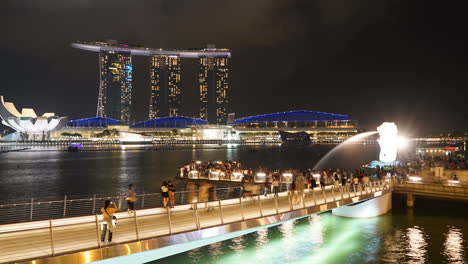 Singapur-–-Ca.-Zeitraffer-Des-Fußgänger--Und-Bootsverkehrs,-Der-Sich-Vor-Dem-Hintergrund-Der-Nächtlichen-Lichter-Singapurs-An-Den-Sandstränden-Der-Skyline-Von-Marina-Bay-Bewegt