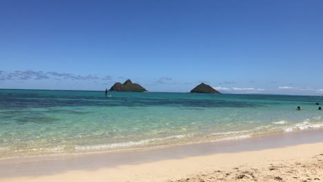 Person-paddle-boarding-on-a-dreamy-tropical-beach-background-in-Lanikai,-Oahu