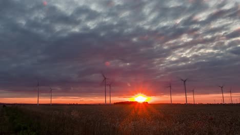 Zoom-in-timelapse-of-a-colorful-sunset-over-a-windmill-farm