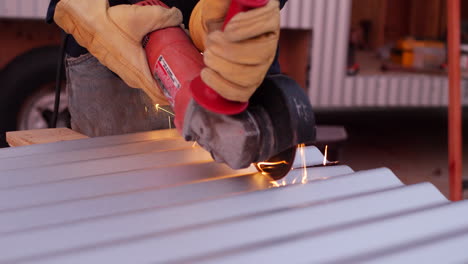 A-construction-worker-using-a-power-tool-angle-grinder-to-cut-metal-and-send-glowing-bright-sparks-flying-in-slow-motion