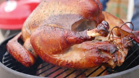 Close-up-of-delicious-looking-turkey-cooking-on-a-small-smoker,-steaming-and-dripping-juices