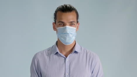 Front-view-shot-of-young-man-putting-on-hygienic-mask