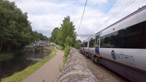 Static-Shot-of-a-Northern-Train-Passing-By-Canal-Locks-as-it-Travels-Away-from-Leeds-on-a-Summer’s-Day-in-Slow-Motion