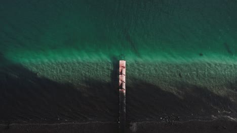 Birds-eye-view-of-empty-wooden-dock-on-a-lake-with-turquoise-water