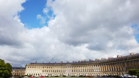Slow-Motion-Closeup-of-The-Royal-Crescent-in-Bath,-Somerset-Panning-Out-Upwards-towards-Blue-Sky-with-White-Clouds-on-a-Summer’s-Day