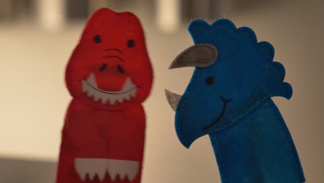 A-red-tyrannosaurus-rex-finger-puppet-and-a-blue-triceratops-talk-together