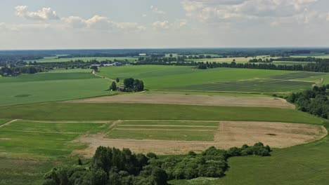 Forward-moving-aerial-of-fields-and-a-farmhouse-in-summer