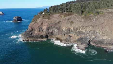 Drone-flies-sideways-looking-at-a-lighthouse-on-a-cliff-near-the-ocean