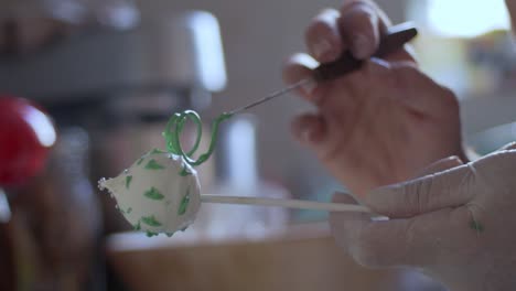 Woman-decorating-cake-pops-with-green-coloured-melted-chocolate