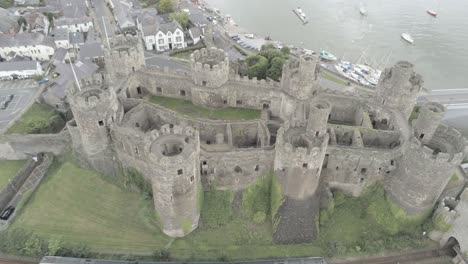 Medieval-landmark-historical-Conwy-castle-aerial-view-above-Welsh-seaside-landscape-train-passing-underneath