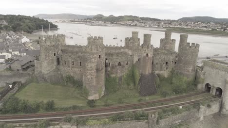 Aerial-view-above-Conwy-castle-Welsh-medieval-town-historic-landmark-rising-orbit-left-pull-back