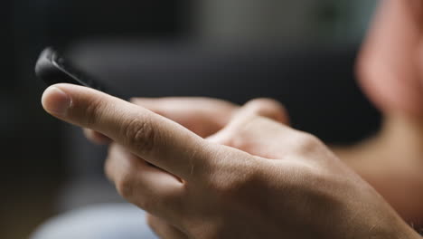Close-up-from-side-of-male-hands-typing-on-smartphone,-shallow-DOF
