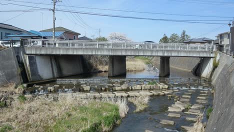 Landscape-view-of-the-local-countryside-of-the-bridge-cross-the-small-canal-white-some-car-passing-on-the-bridge-in-spring-sunshine-day-in-Fukushima-area,-Japan