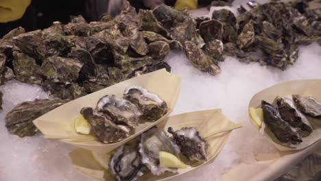 Dolly-shot-of-whole-and-shucked-oysters-on-ice