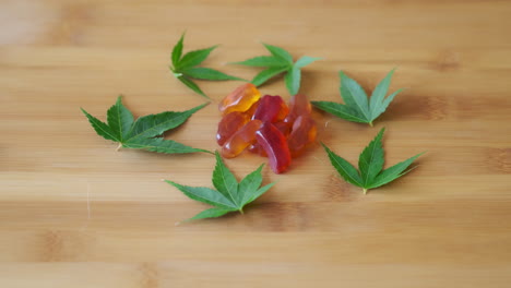 Slow-Motion-Hand-Picking-Out-CBD-Gummy-from-Candy-Pile-Surrounded-by-Marijuana-Leaves