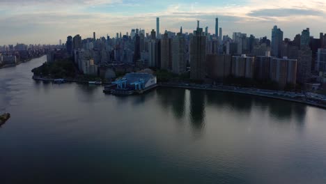 epic-aerial-camera-tilts-up-to-reveal-the-New-York-City-skyline-with-a-nice-reflection-in-the-East-River-at-sunset-tilt-keeps-going-up-to-blue-sky