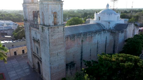 Aerial-closeup-boom-up-with-sun-behind-of-the-Cathedral-de-San-Gervasio-just-after-sunrise-in-Valladolid,-Yucatan,-Mexico