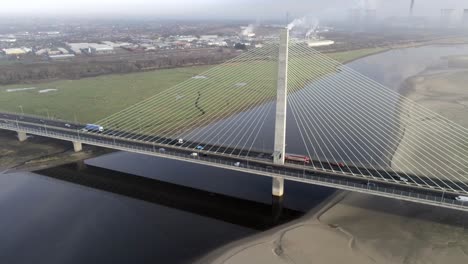 Aerial-pan-right-view-above-busy-traffic-commuting-on-river-Mersey-suspension-bridge-sunrise-misty-morning