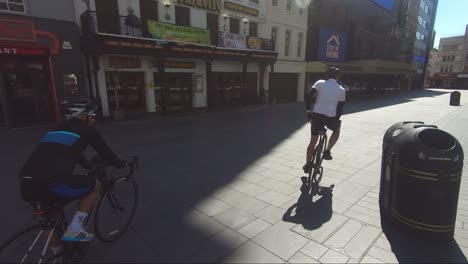 Zwei-Erwachsene-Männliche-Radfahrer-Fahren-Während-Der-Sperrung-In-London-Durch-Den-Leeren-Leicester-Square