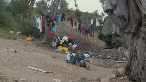 Dos-Niños-Refugiados-Se-Sientan-Solos-Bajo-El-Tendedero-En-El-Campo-De-Refugiados-De-Moria