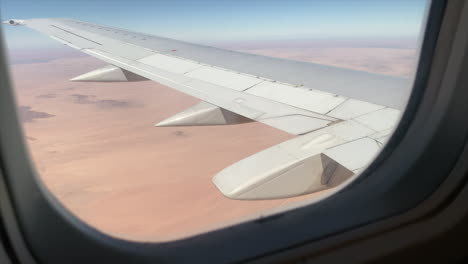 Wide-shot-of-the-wing-of-a-large-aeroplane-in-flight-shot-through-the-plane-window