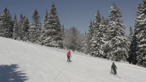 Skier-family-going-downhill-at-Kope-ski-resort-during-winter,-Aerial-pan-right-tracking-shot
